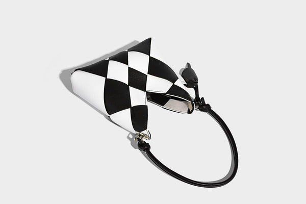 Compact bucket shoulder bag with black-and-white diamond patchwork panels, knotted top handle, gold-tone hardware, and