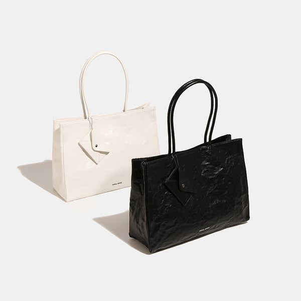 Large glossy crinkled rectangular tote bag with long double handles and hanging envelope snap tag, detail view 2