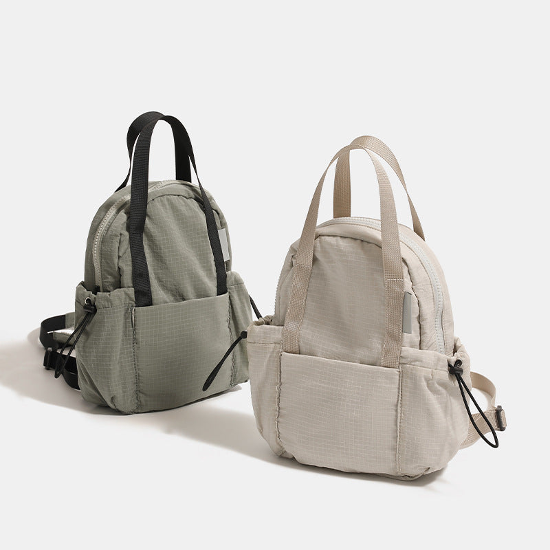 Mini rounded convertible backpack handbag in matte ripstop fabric with dual top handles, adjustable straps, and side, front