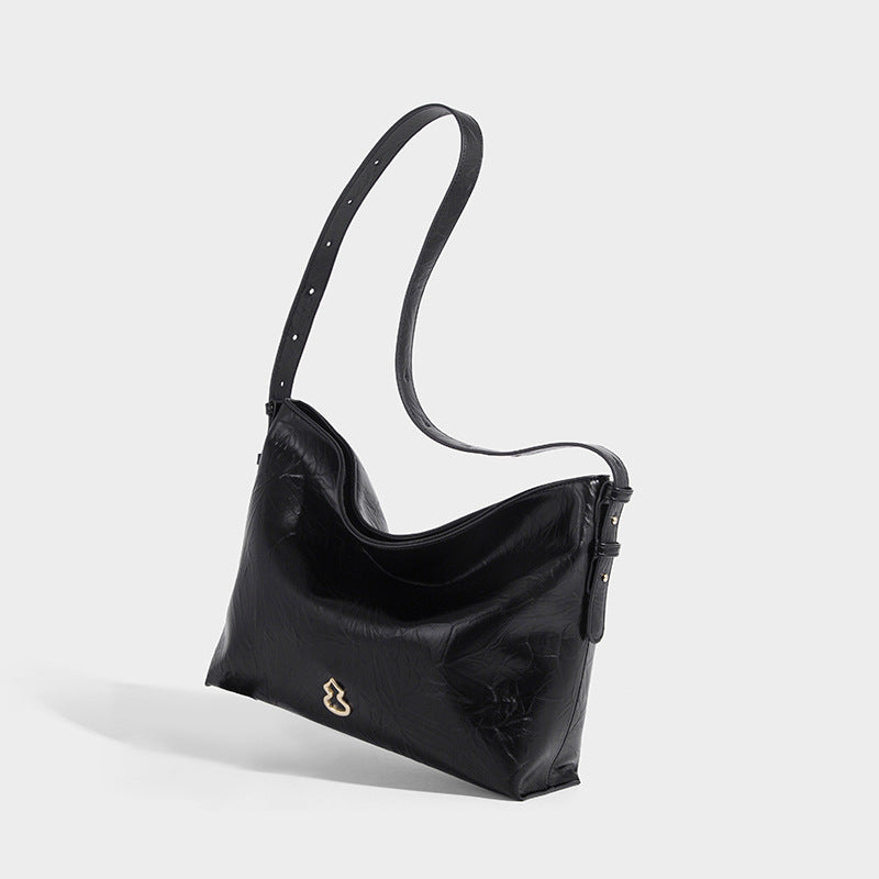 Large slouchy hobo shoulder bag in glossy crinkle leather-look finish with gold-tone emblem hardware and adjustable strap