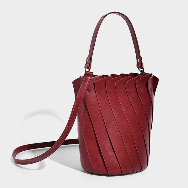 Structured pleated-panel bucket bag with curved top handle and detachable adjustable shoulder strap in smooth matte, detail