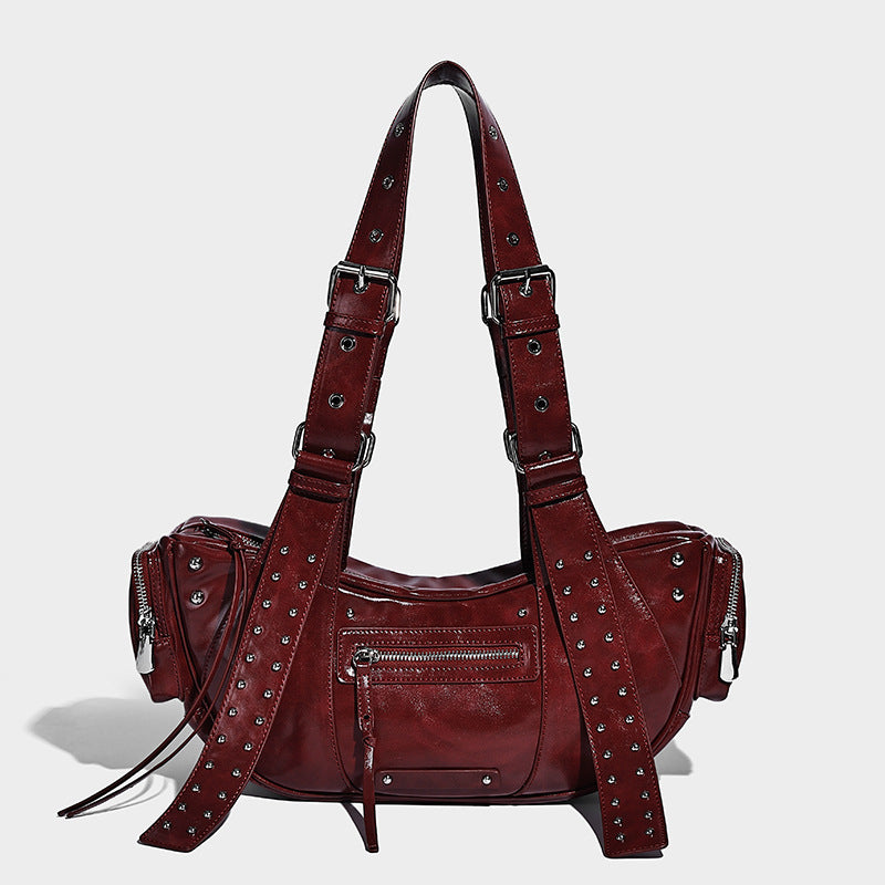 Glossy black crescent shoulder bag with silver-tone rivets, multiple zip pockets, and long adjustable studded straps, detail