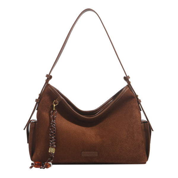 Caramel brown slouchy hobo shoulder bag with matte suede-like finish, braided tassel charm, brass-tone hardware, and, detail