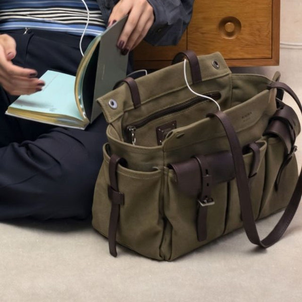 Large olive canvas shoulder tote bag with multiple front buckle-strap pockets and dark brown leather-look trim, detail view 2