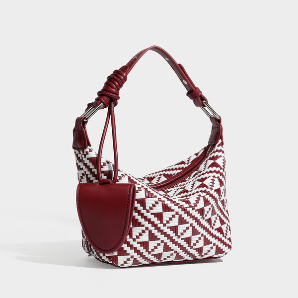 Kleine gewebte Schultertasche mit geometrischem Schwarz-Weiß-Muster, glatten dunkelbraunen Details in Lederoptik, geknotetem verstellbarem Riemen, Seitenansicht