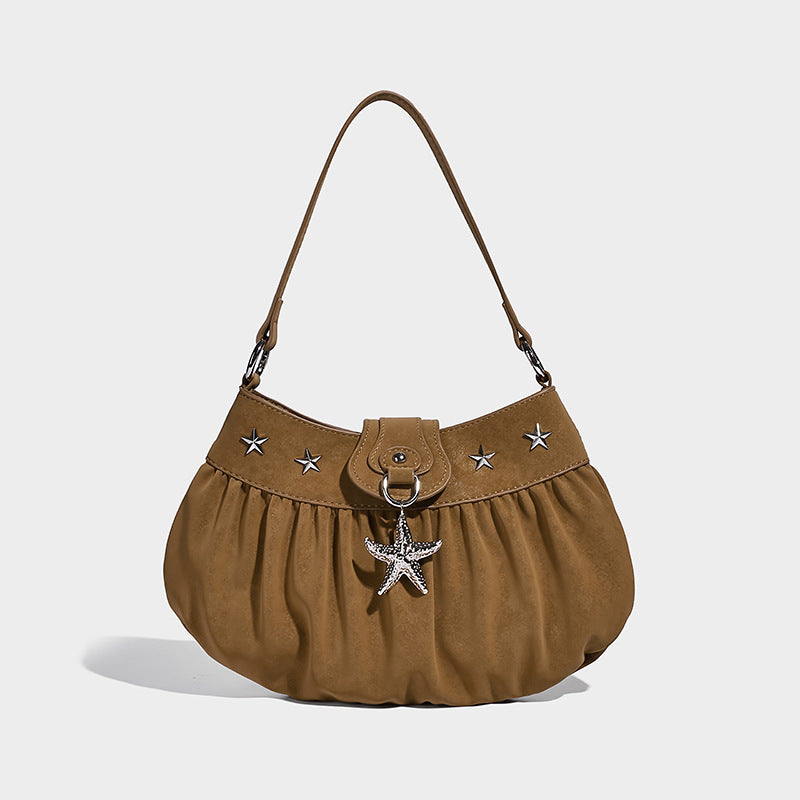 Ruched shoulder bag with curved flap, silver star studs, dangling starfish charm, and adjustable crossbody strap, detail view