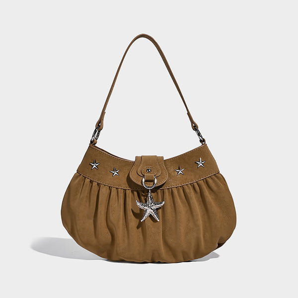 Ruched shoulder bag with curved flap, silver star studs, dangling starfish charm, and adjustable crossbody strap, detail view