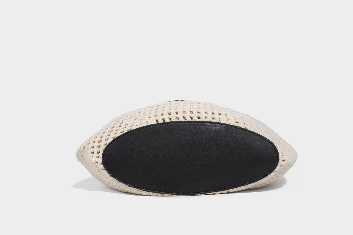 Cream openwork crochet hobo bag with black leather-look strap and trim patch accent, slouchy teardrop silhouette, detail view