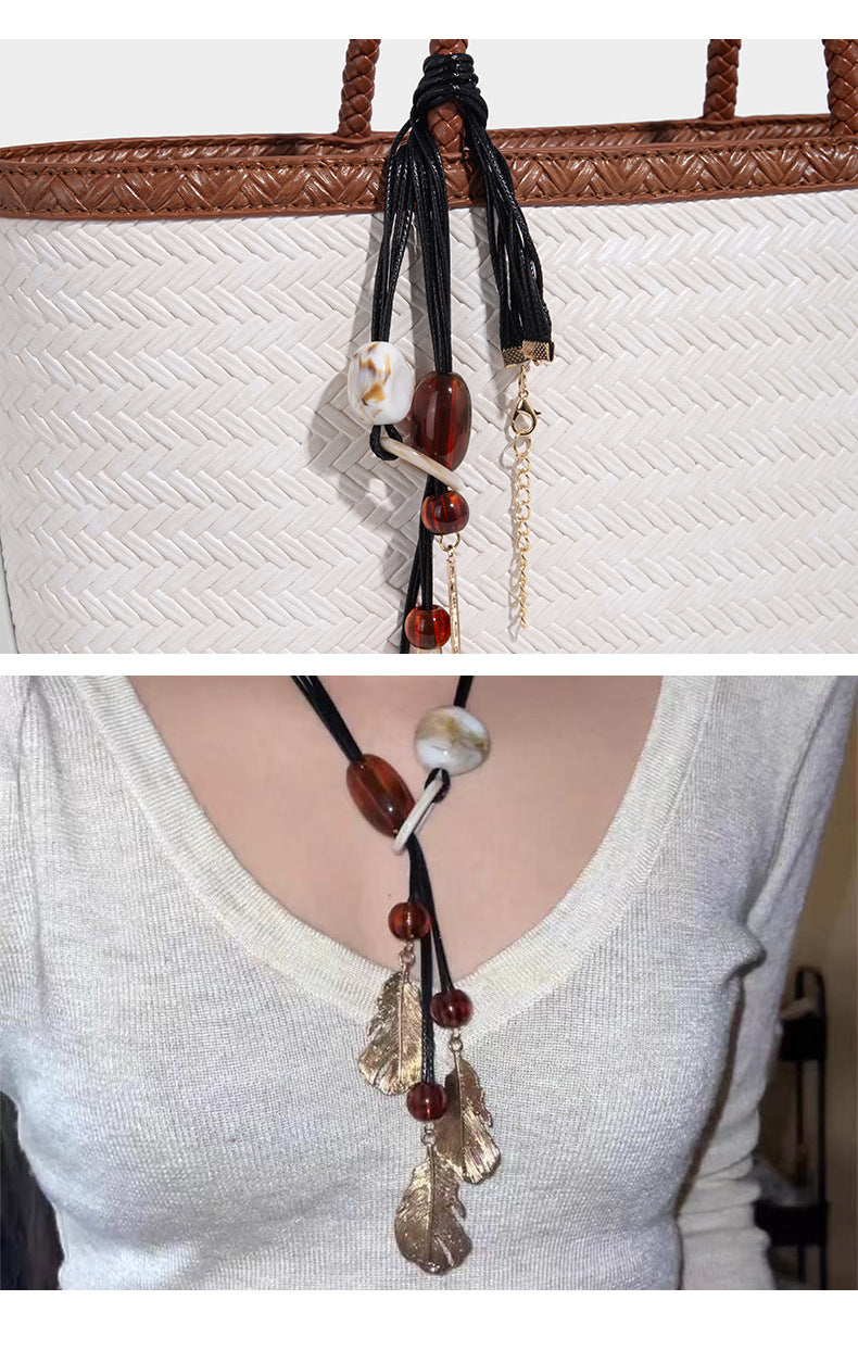 Structured woven-texture tote bag with brown braided top handles, decorative tassel charm, and detachable shoulder strap