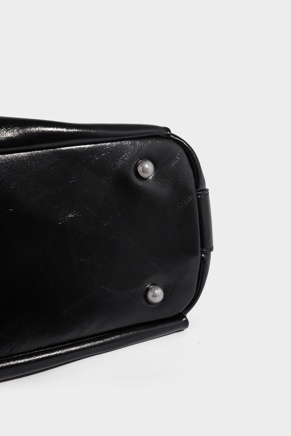 Glossy black slouchy hobo shoulder bag with zip closure, silver-tone ring hardware, and adjustable crossbody strap, detail