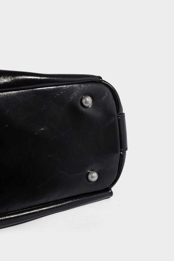 Glossy black slouchy hobo shoulder bag with zip closure, silver-tone ring hardware, and adjustable crossbody strap, detail
