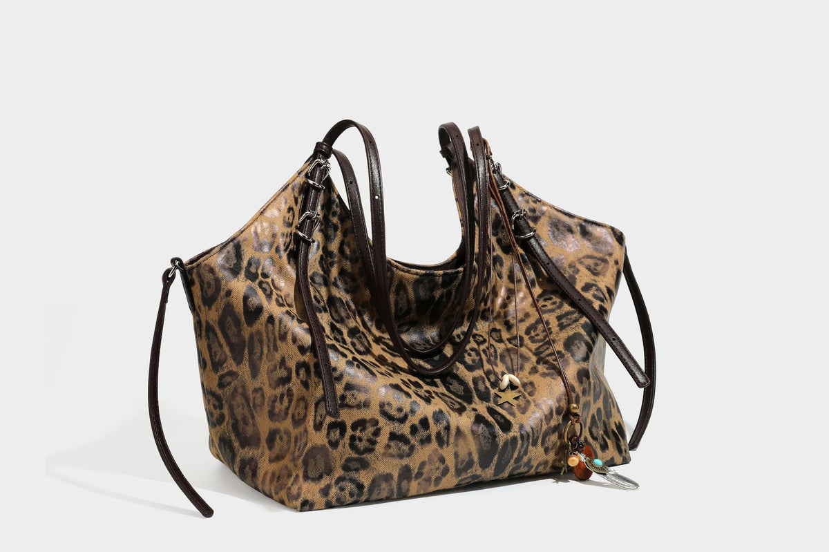 Slouchy leopard-print shoulder tote bag in tan and brown with long double straps, side tie straps, and dangling charm, detail