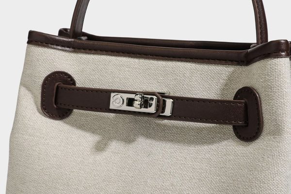 Small structured beige canvas top-handle bag with dark brown leather-look trim, silver turn-lock hardware, and detachable