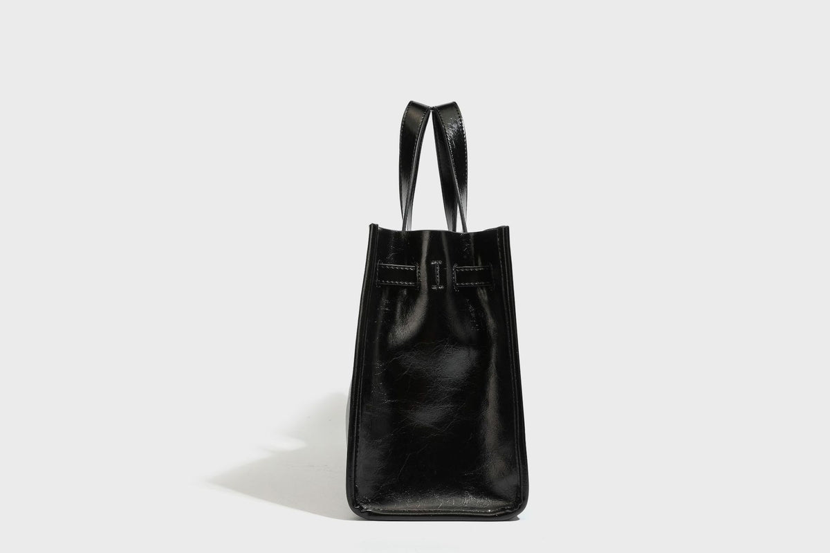 Strukturierte, glänzende Tote-Bag in Lederoptik mit silberfarbenem Drehverschluss, zwei Tragegriffen und abnehmbarem Schulterriemen, Detailansicht