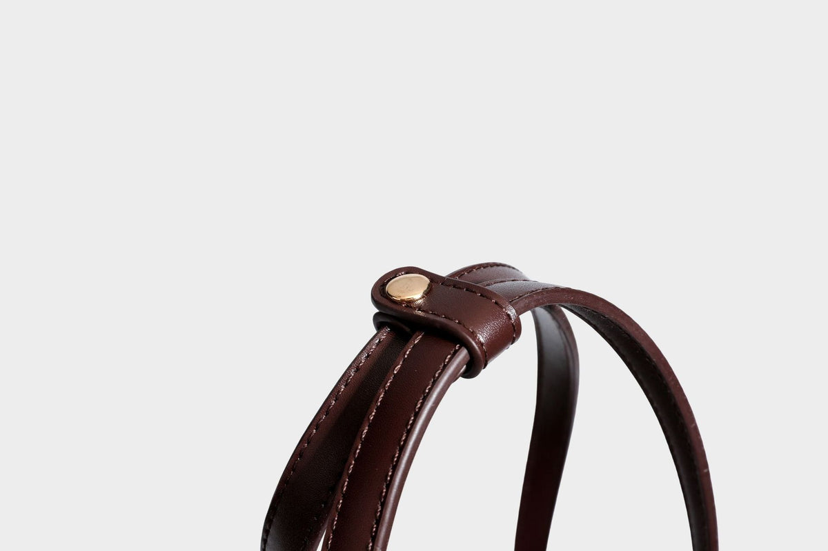 Structured trapezoid shoulder bag in dark brown pebbled leather-look finish with slim double straps, top zip closure, side