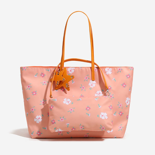 Large reversible floral print tote bag with slim shoulder straps, star charm hardware, and matching zip pouch, detail view 2