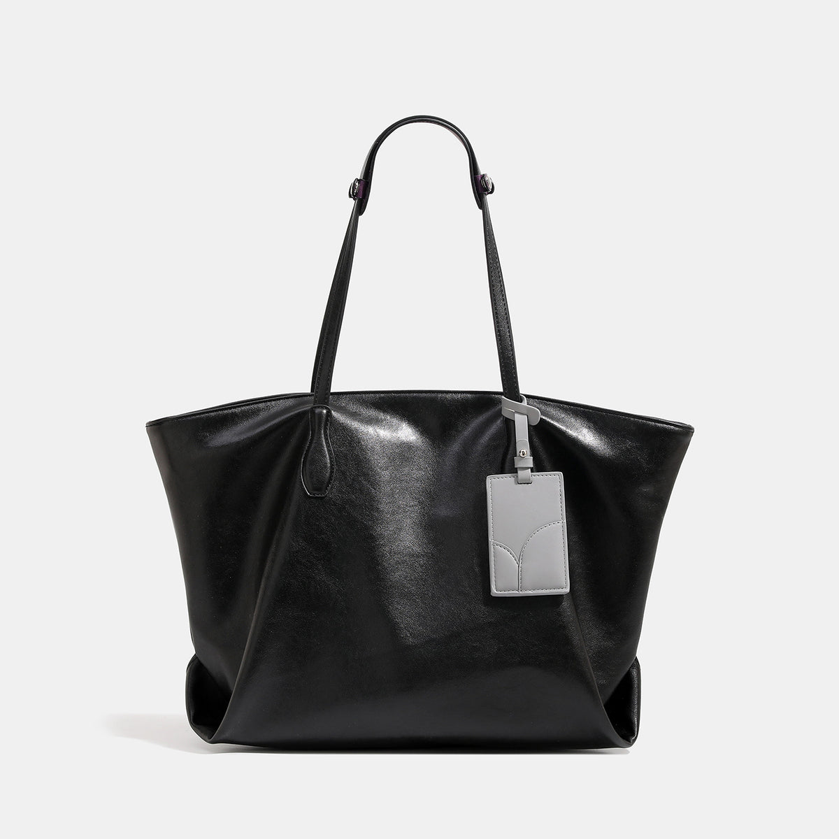 Large soft trapezoid tote bag with leather-look finish, dual shoulder straps, and gray hanging card tag, front view