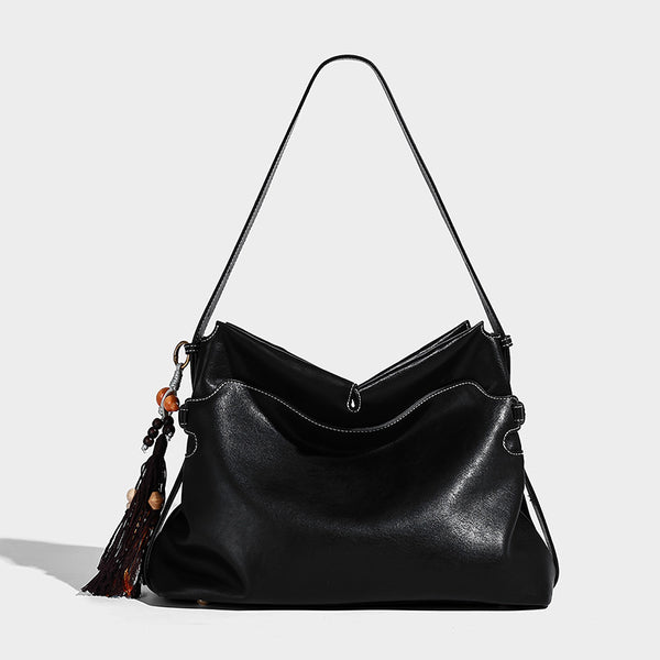 Large slouchy leather-look hobo tote bag with open top, adjustable shoulder strap, and colorful tassel bead charm, detail