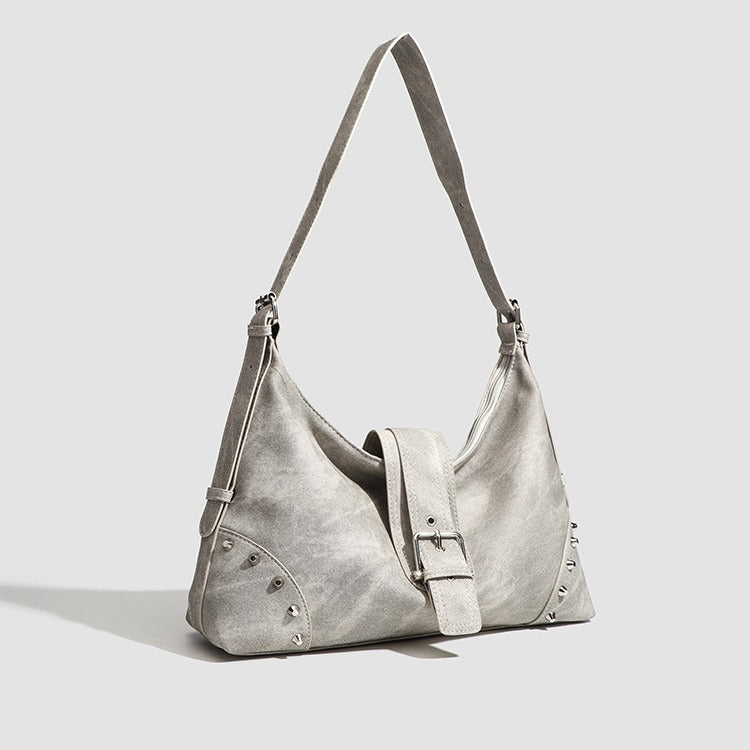 Slouchy trapezoid hobo shoulder bag with distressed textured finish, silver rivet corner accents, centre buckle strap, and