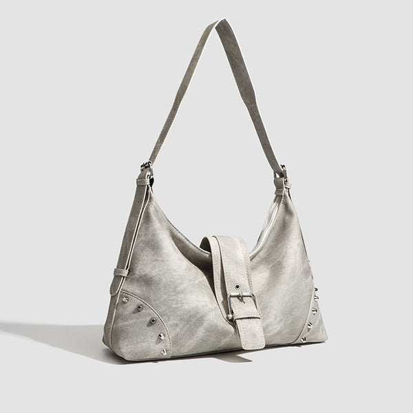 Slouchy trapezoid hobo shoulder bag with distressed textured finish, silver rivet corner accents, centre buckle strap, and