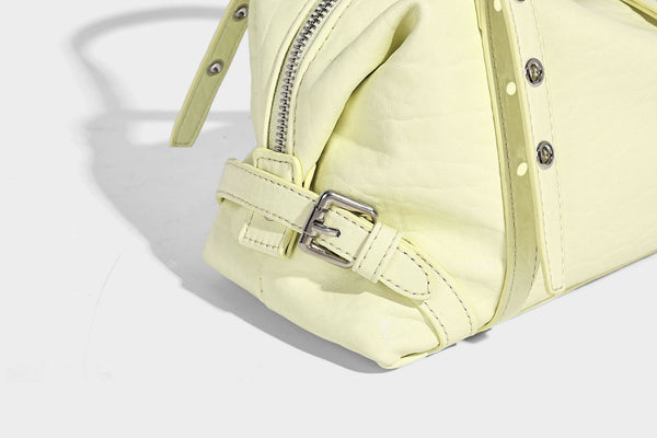 Pale yellow leather-look barrel bag with silver grommet-studded shoulder straps, top zip closure, and pink tulip floral