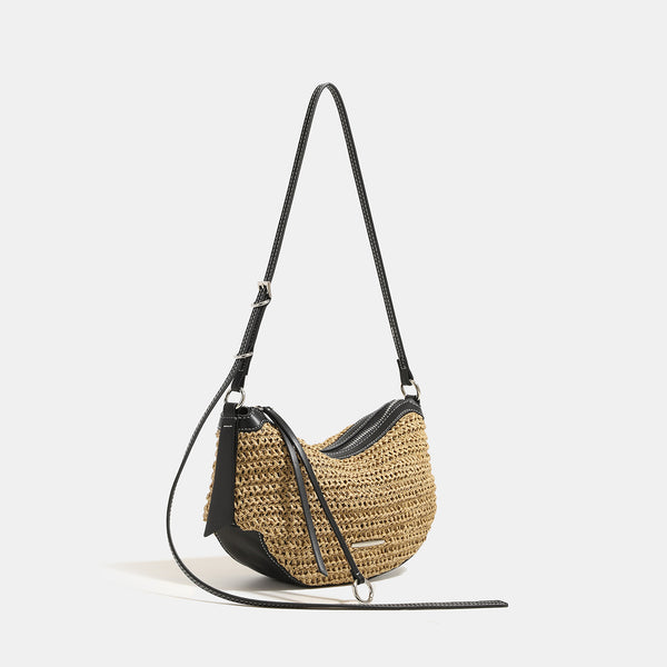 Compact crescent-shaped woven straw crossbody bag with black leather-look trim, top zip closure, and adjustable shoulder