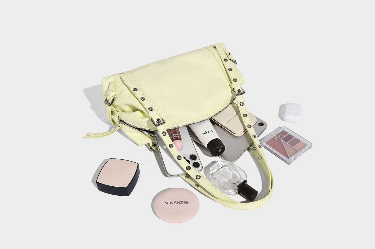 Pale yellow leather-look barrel bag with silver grommet-studded shoulder straps, top zip closure, and pink tulip floral