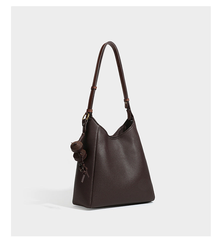 Hobo-Schultertasche in dunklem Espresso mit genarbter Oberfläche, warmen cognacfarbenen Details, verstellbarem schmalem Riemen, goldfarbenen Ringbeschlägen und geknotetem
