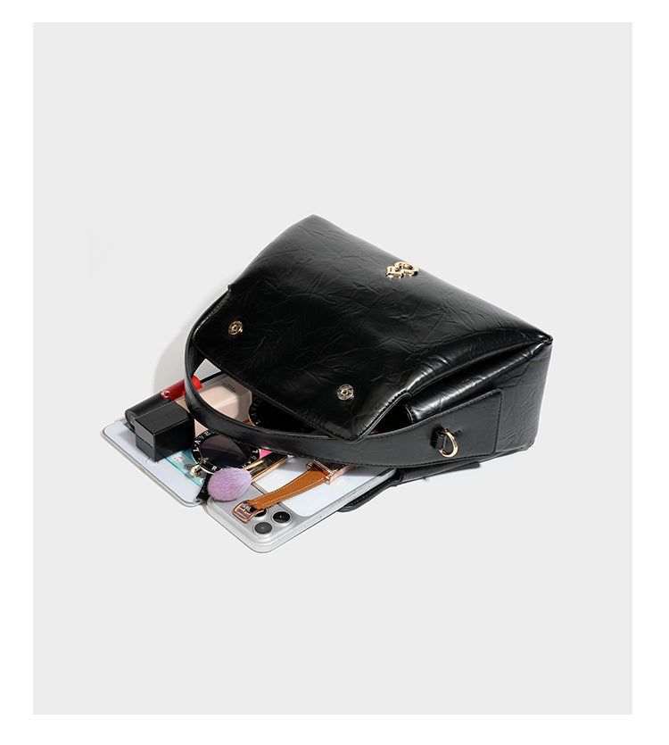 Glänzende, geknautschte Trapez-Schultertasche mit Überschlagverschluss, goldfarbenen Logo-Beschlägen, Tragegriff und abnehmbarem, verstellbarem Schulterriemen