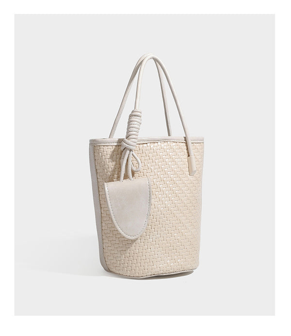 Structured woven-texture leather-look bucket bag in brown with knotted top handles, small front flap pouch, and adjustable