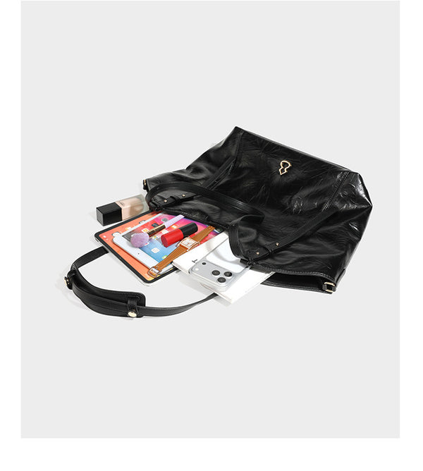 Große, glänzende Tote-Bag aus schwarzem Lederimitat mit geknitterter Optik, lässig fallender Trapezsilhouette, zwei Schulterriemen und goldfarbenen
