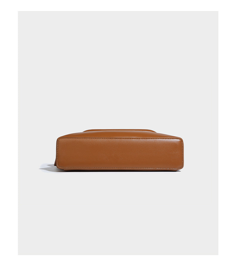 Compact structured baguette shoulder bag with smooth leather-look finish, zip top, and adjustable silver-buckle strap, detail