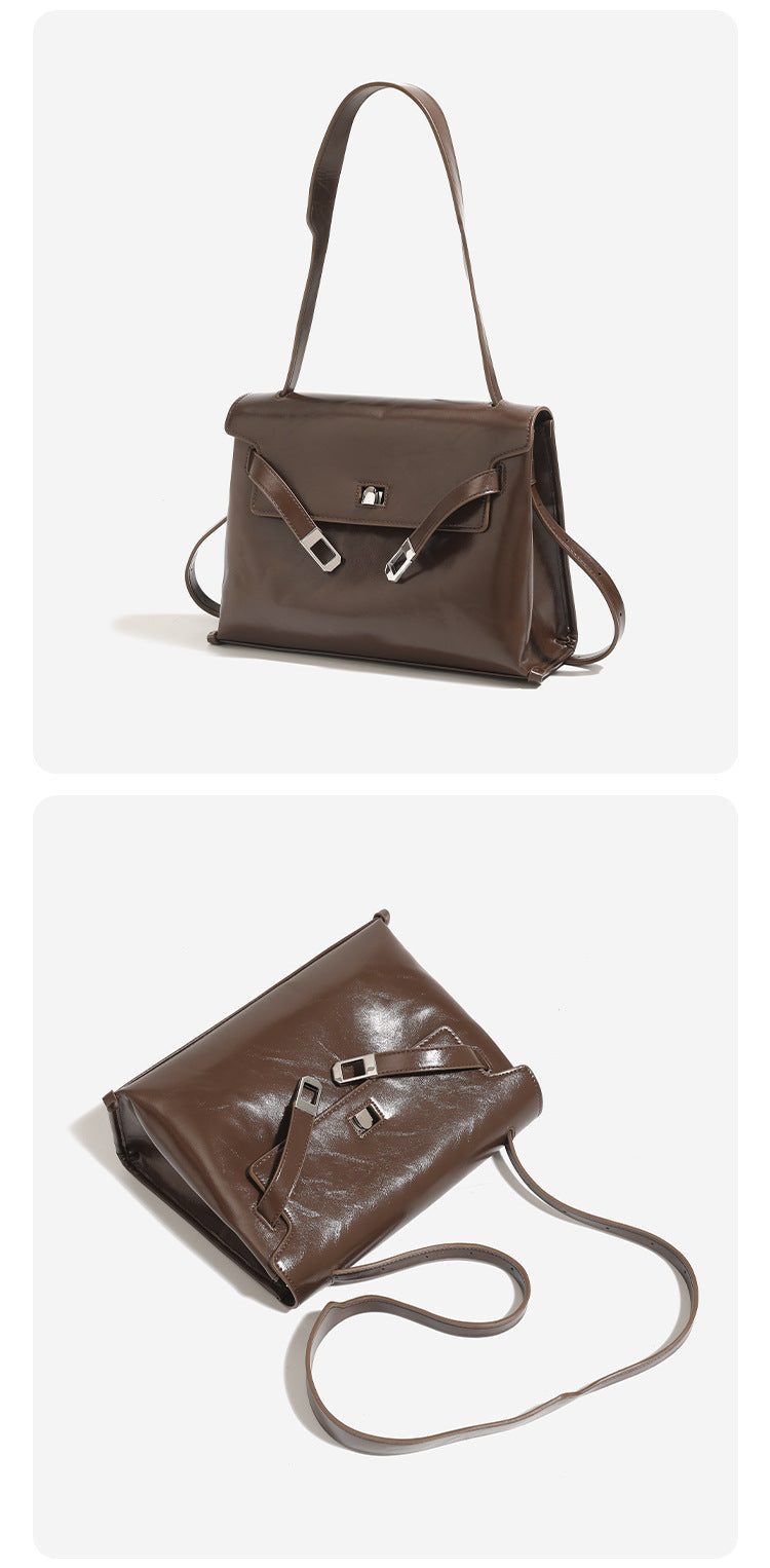 Structured trapezoidal flap satchel bag with silver-tone turn-lock clasp, decorative front strap tabs, gusseted sides, and
