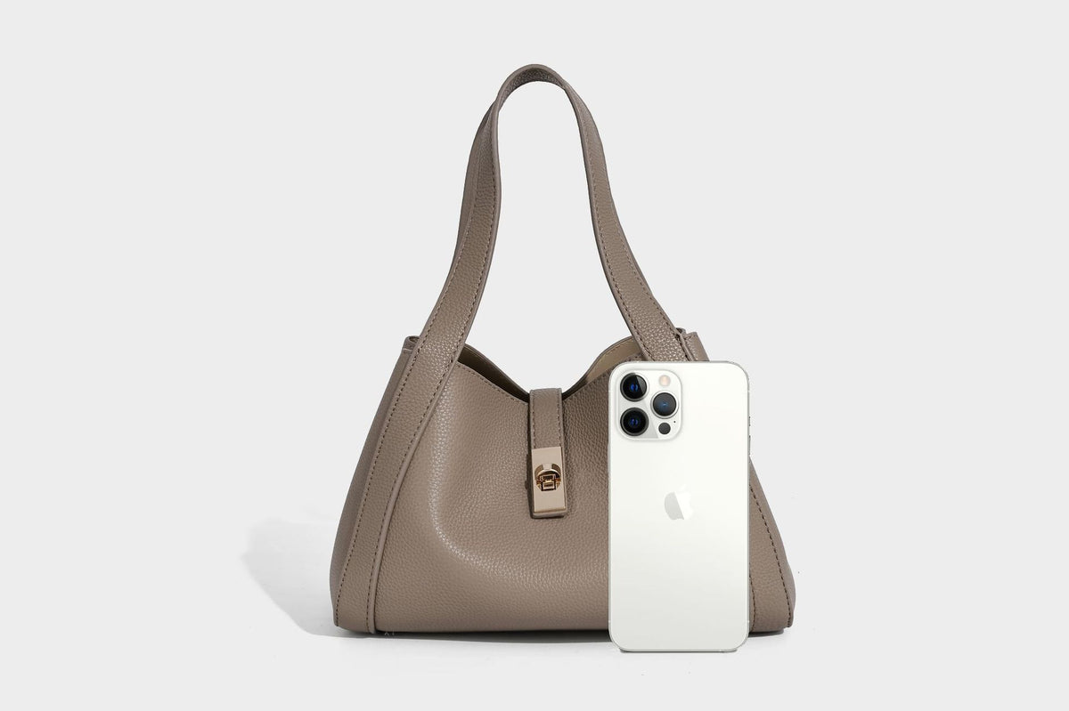 Structured trapezoid tote bag in taupe pebbled leather-look finish with gold-tone turn-lock hardware, dual top handles, and