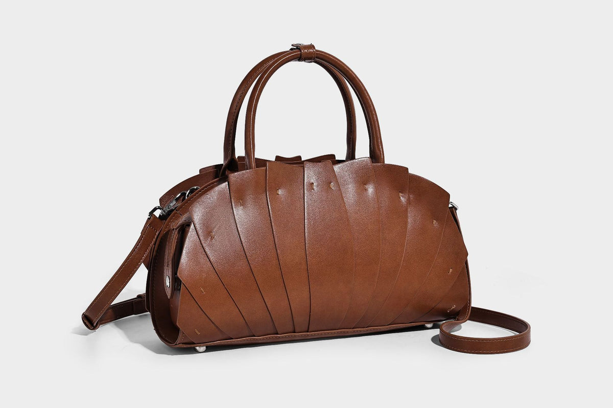 Structured dome satchel with fan-pleated leather-look exterior, dual top handles, and detachable shoulder strap, detail view