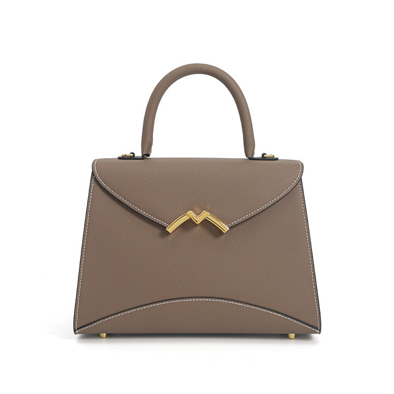 Structured trapezoid top-handle satchel in golden brown cross-grain textured finish with gold M-shaped clasp hardware and