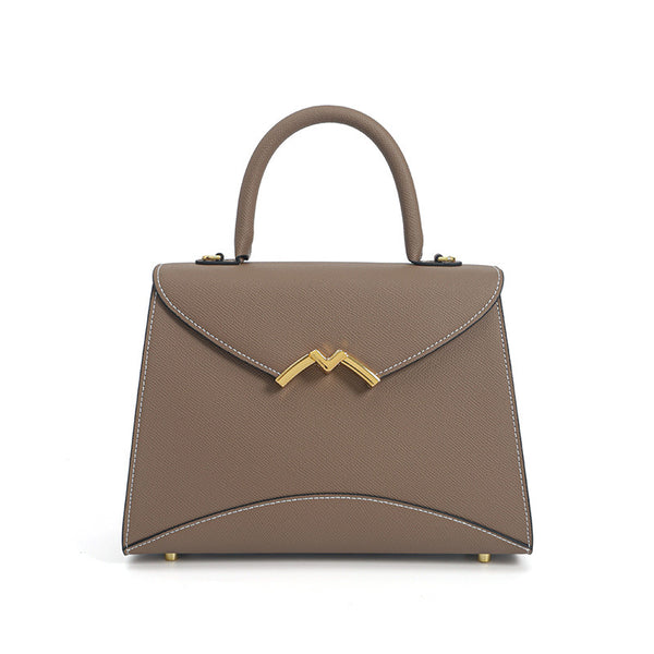 Structured trapezoid top-handle satchel in golden brown cross-grain textured finish with gold M-shaped clasp hardware and