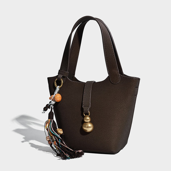 Kleine Beuteltasche mit genarbter, matter Oberfläche, antikgoldfarbenen Ringbeschlägen, Perlen- und Quastenanhänger, kurzen Henkeln und