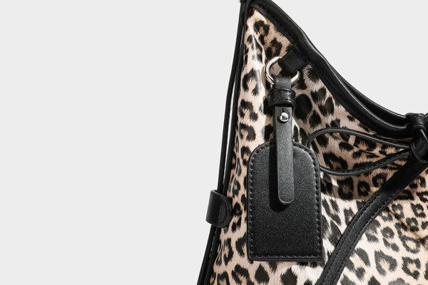Slouchy leopard print shoulder hobo bag with black leather-look trim, tie-top closure, and single long strap, detail view 33