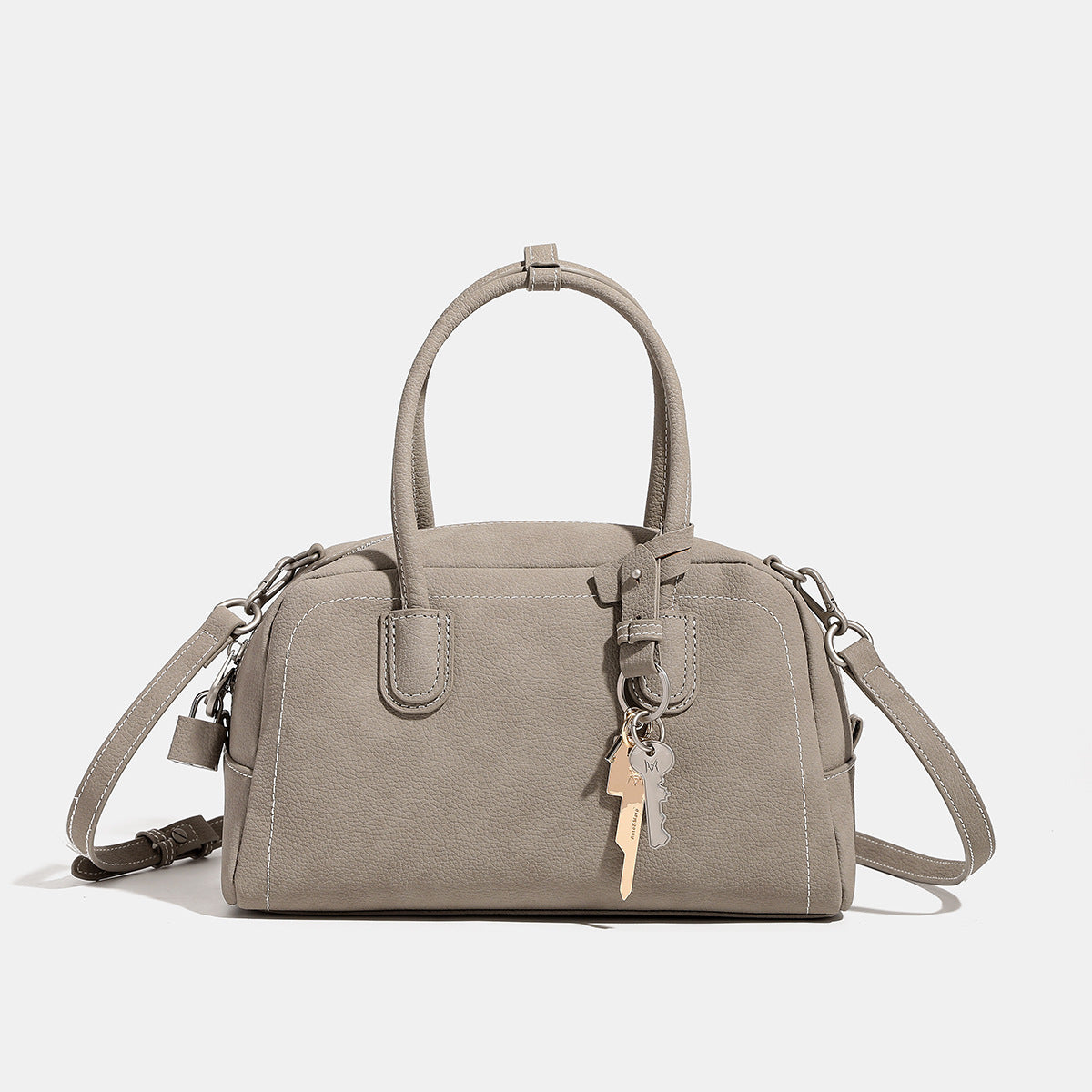 Kompakte, strukturierte Henkeltasche mit matter genarbter Oberfläche, geknoteten Doppelgriffen, goldenem Schlüsselanhänger und abnehmbarem, Detailansicht