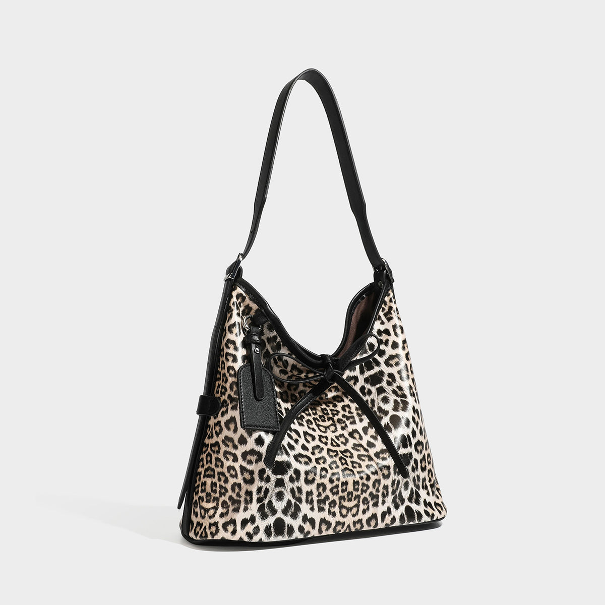 Slouchy leopard print shoulder hobo bag with black leather-look trim, tie-top closure, and single long strap, front view