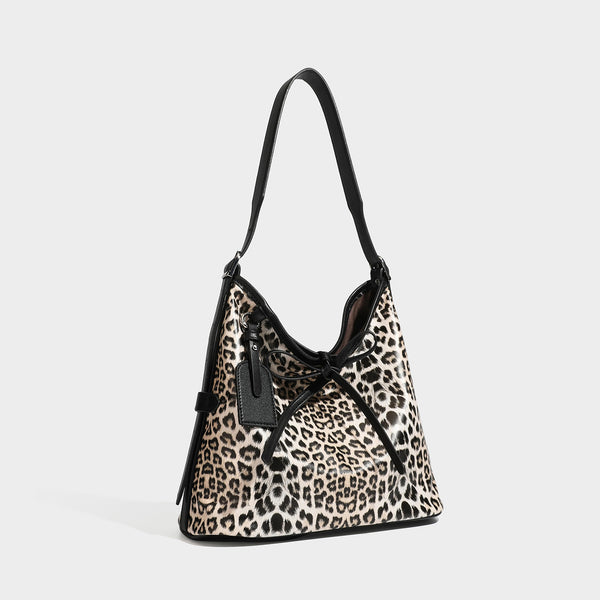 Slouchy leopard print shoulder hobo bag with black leather-look trim, tie-top closure, and single long strap, front view