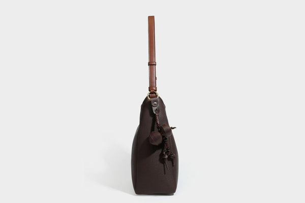 Hobo-Schultertasche in dunklem Espresso mit genarbter Oberfläche, warmen cognacfarbenen Details, verstellbarem schmalem Riemen, goldfarbenen Ringbeschlägen und geknotetem