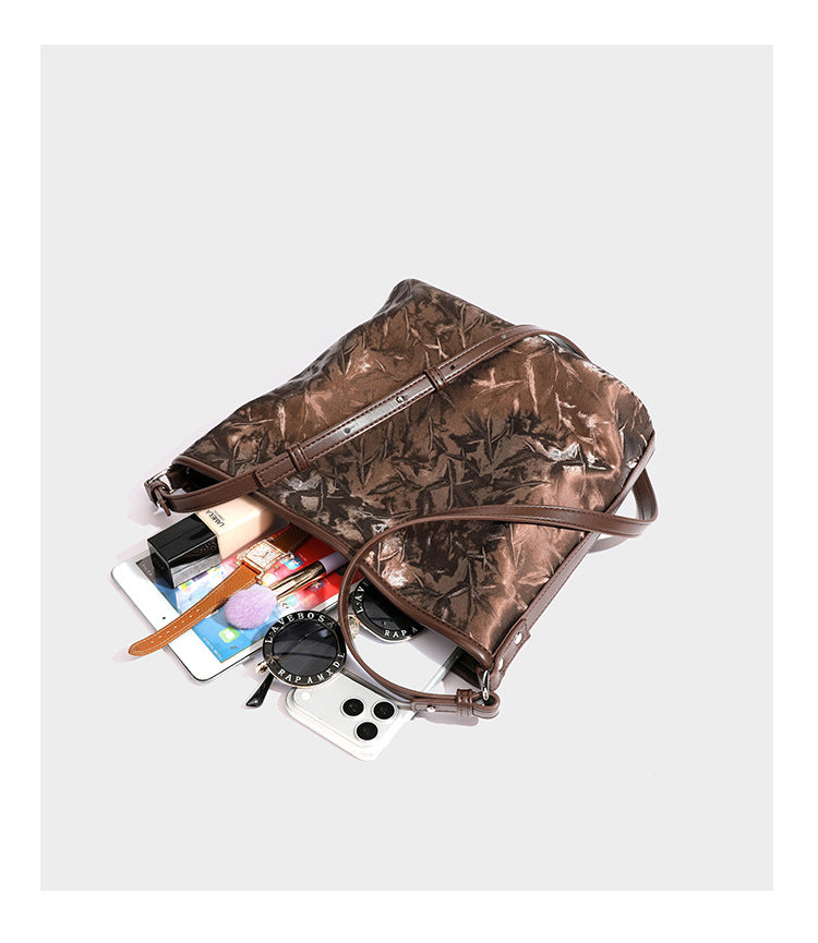 Große Hobo-Schultertasche mit Knitterglanz in Dunkelbraun, schmalem verstellbarem Riemen, geknoteten Metalldetails und seitlich angesetzter Klappe