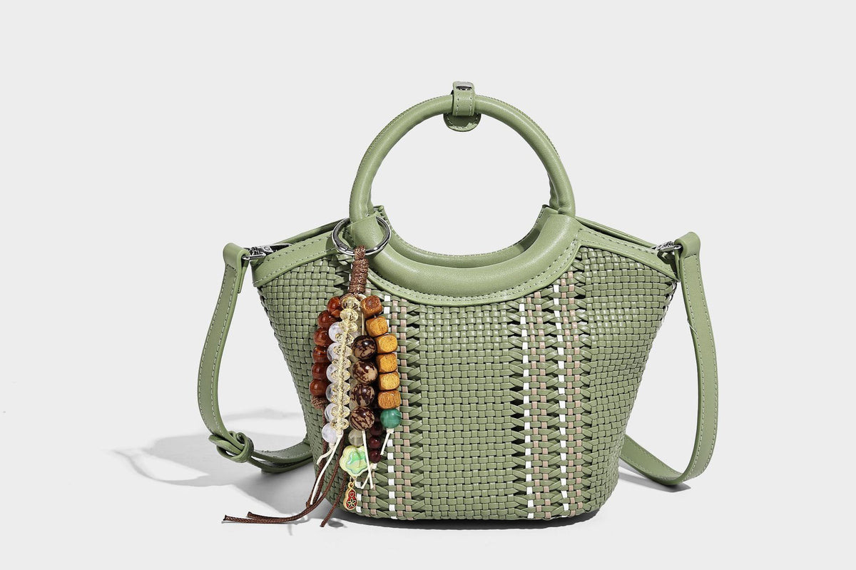 Kleine strukturierte Beuteltasche aus geflochtenem Material mit rundem Tragegriff in Lederoptik, silberfarbenen Beschlägen und perlenbesetztem Quastenanhänger, Detail