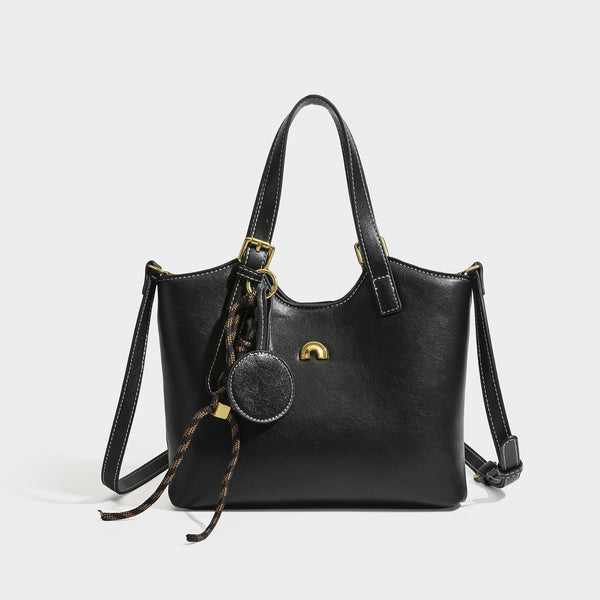 Structured smooth leather-look tote bag with long shoulder strap, gold-tone hardware, and hanging tassel-coin charm, detail