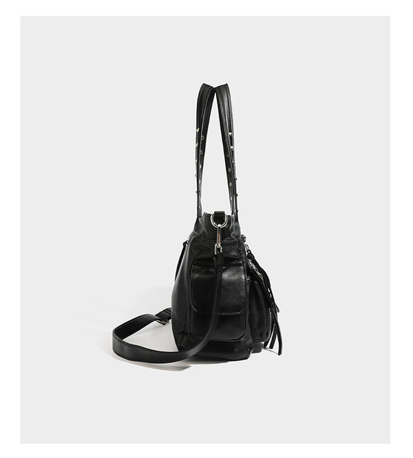 Black leather-look tote bag with silver pyramid studs on handles and front panel, multiple flap and zip exterior pockets