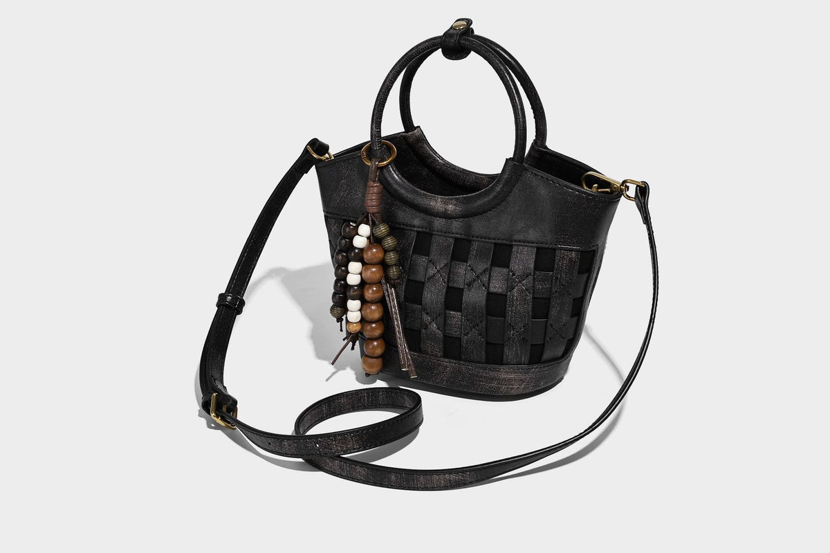 Small woven-panel bucket bag with circular ring handles, beaded tassel charm, and detachable crossbody strap in brown, detail