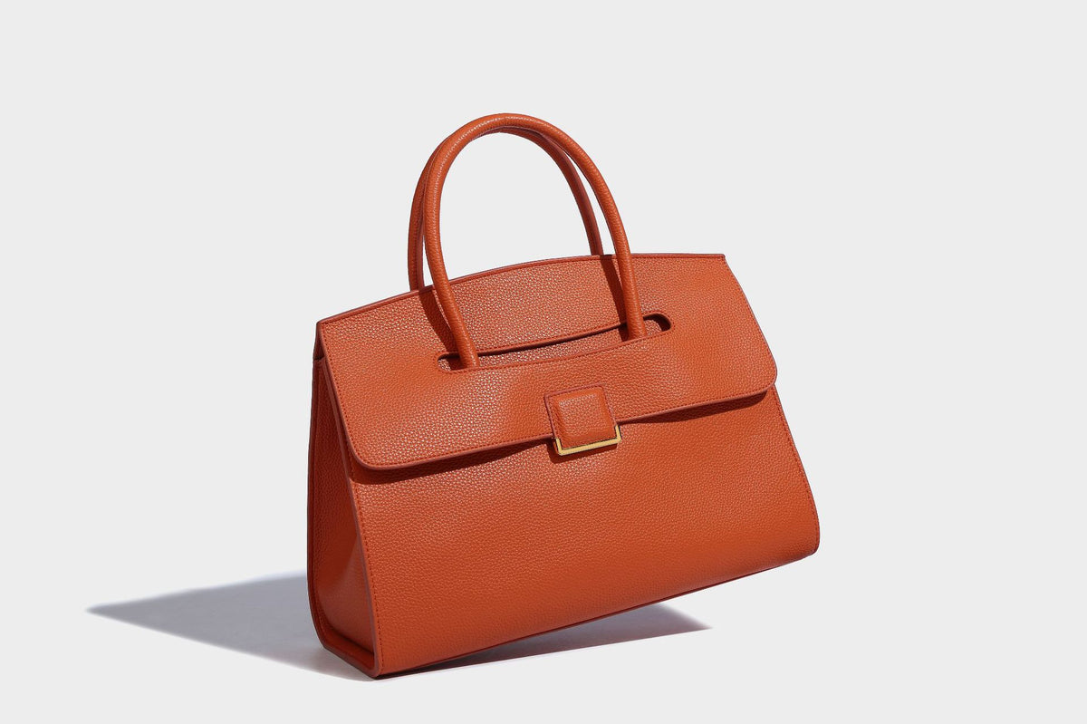 Strukturierte, trapezförmige Henkeltasche mit matt genarbter Oberfläche, vorderer Klappe und quadratischem Drehverschluss in Goldoptik, Detailansicht