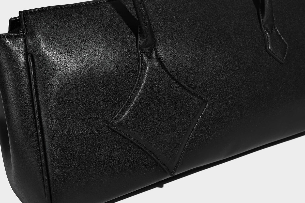 Strukturierte Tote-Bag in schwarzer Lederoptik mit Drehverschluss in Vorhängeschloss-Optik, dekorativen Riemendetails und abgerundeten Doppelhenkeln